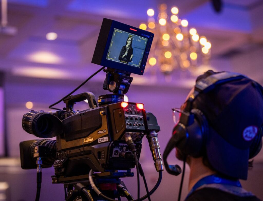 A camera technician from Soundbox Productions looking through their camera during the live recording of the LiONS LAIR Pitch Competition and Gala